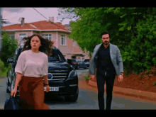 a man and a woman walking down a street with a license plate that says mh 90