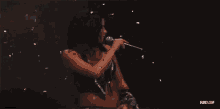 a woman is singing into a microphone with confetti falling around her .