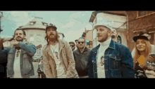 a group of men are standing next to each other on a street in front of a crowd of people .