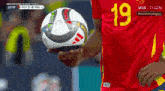 a soccer player with the number 19 on his jersey holds a soccer ball