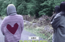 a woman wearing a pink sweater with a heart cut out on the back