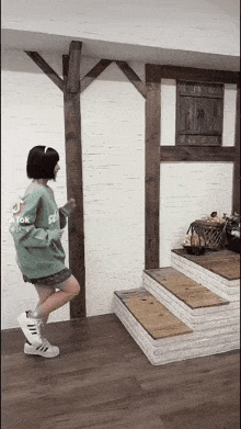 a woman in a green sweatshirt is dancing in a room