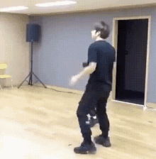 a man in a black shirt and black pants is dancing in a dance studio .