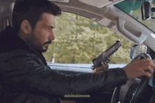 a man is holding a gun while driving a car ..