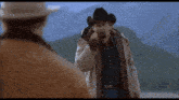 a man in a cowboy hat holds a gun in his right hand