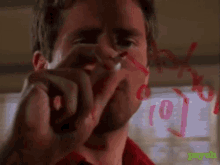 a man in a red shirt writes the number 10 on a whiteboard