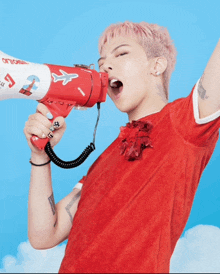 a man in a red shirt is shouting into a megaphone that says " optional "