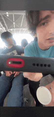 a man in a blue shirt is holding a black item with a red circle on it
