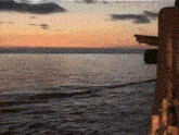 a sunset over a body of water with a building in the background