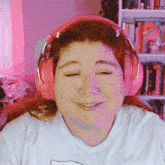 a woman wearing pink headphones and a hello kitty shirt smiles