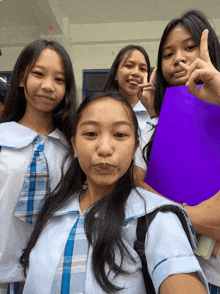 a group of young girls pose for a picture with one girl holding a purple folder