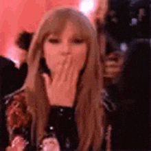 a woman is blowing a kiss with her hand .