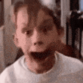 a close up of a child 's face with his mouth open and a surprised look on his face .