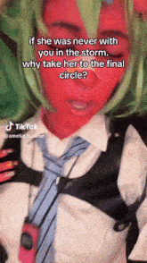 a woman with a red face and green hair is wearing a tie and vest .