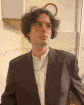 a man in a suit is standing in front of a wall clock that shows the time as 2:30
