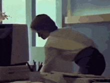 a woman is sitting at a desk in front of a computer and a window .
