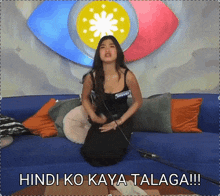 a woman is sitting on a blue couch with the words hindi ko kaya talaga written below her