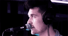 a man wearing headphones and singing into a microphone .