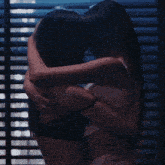 a man and woman are kissing in front of a window