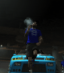 a man smoking a cigarette in front of a blue car that says flow