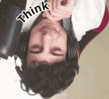 a man wearing headphones is upside down and has the word think on his face