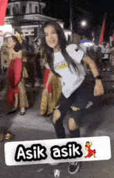 a girl is dancing in front of a sign that says asik