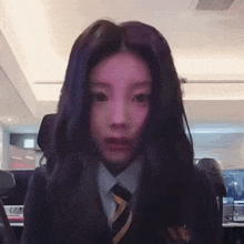 a girl in a suit and tie looks at the camera with purple hair