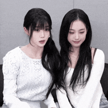 two women are sitting next to each other and one is wearing a white top