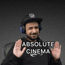 a man wearing headphones and a hat says " absolute cinema " with his hands up