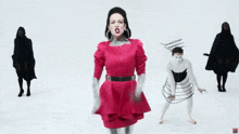 a woman in a red dress is standing in front of a group of people