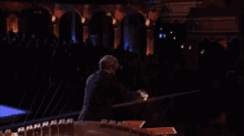 a man in a suit is playing a piano in a dark room