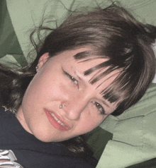 a woman with a nose ring is laying on a green blanket