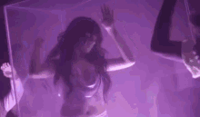 a woman is dancing in a purple room in front of a purple curtain .