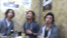a blurry photo of three men sitting in front of a wall with a sign that says ' whisky ' on it