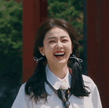 a woman with pigtails and a tie is smiling