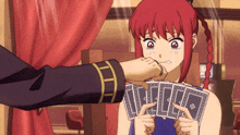 a girl with red hair is crying while a man holds playing cards in front of her