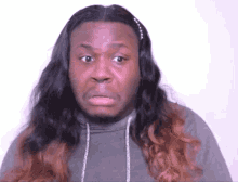 a man with long hair is wearing a grey sweatshirt