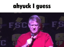 a man in a red shirt is holding a microphone in front of a sign that says fsc fs