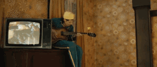 a man is playing a guitar in front of a tv