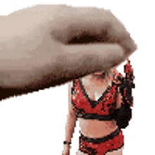 a hand is holding a statue of a woman in a red bra and shorts .