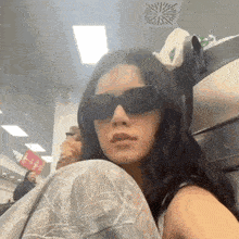 a woman wearing sunglasses is sitting in a chair in a room .