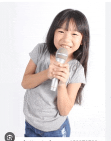 a little girl is holding a silver microphone in her hands