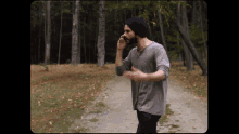 a man talking on a cell phone while walking down a path in the woods