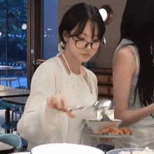 a woman wearing glasses is serving food to another woman at a table