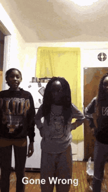 three girls are standing in front of a refrigerator and a sign that says gone wrong on it