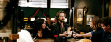 a group of people are sitting at a table in a restaurant drinking .