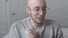 a bald man wearing glasses is sitting at a table eating a meal .