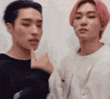 two young men are standing next to each other and one of them is pointing at the camera .