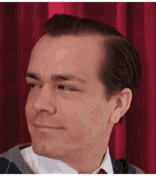a man wearing a sweater and tie looks to his left