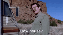 a man standing in front of a trailer with the words cow house below him